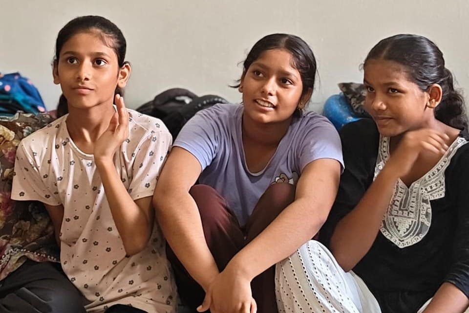 Three girls sitting together against a classroom wall during an Insightio session