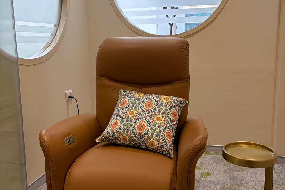 A leather recliner with an embroidered cushion beside the round windows of the Insightio consulting room